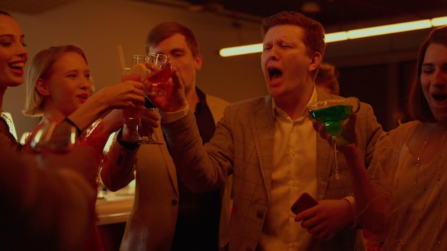 Felice gruppo di persone che tintinnano i bicchieri nel bar Amici che festeggiano nel club