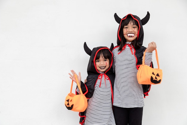 Felice Halloween! due bambini in costumi di Halloween e con zucche su sfondo bianco