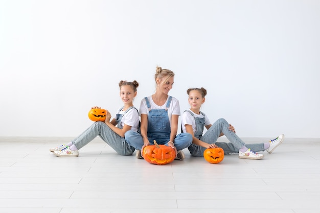 Felice halloween e concetto di vacanze - Una madre e le sue figlie con le zucche. Famiglia felice che prepara per Halloween.