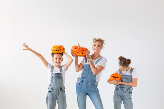 Felice halloween e concetto di vacanze - Una madre e le sue figlie con le zucche. Famiglia felice