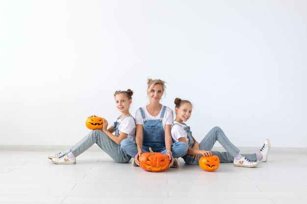 Felice halloween e concetto di vacanze - Una madre e le sue figlie con le zucche. Famiglia felice