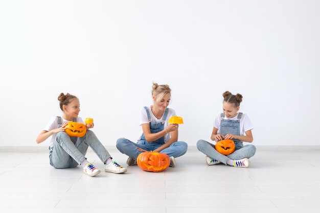 Felice halloween e vacanze concetto - una madre e le sue figlie con le zucche. Famiglia felice che si prepara per Halloween.