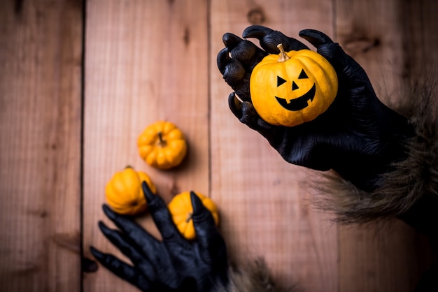 Felice Halloween. Mani di lupo mannaro o zombie che dipingono una zucca spaventosa per una festa dolcetto o scherzetto. copia spazio per il testo