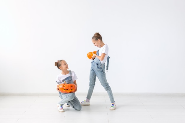 Felice Halloween, vacanze e concetto di infanzia - simpatiche sorelle gemelle ragazze con zucche Jack-o'-lantern che si divertono mentre trascorrono del tempo in casa