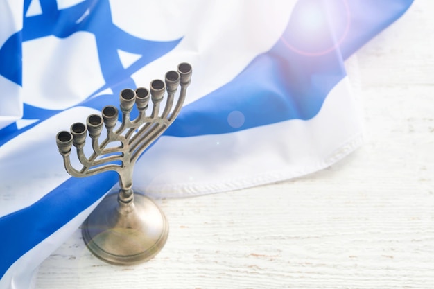 Felice Hanukkah Hanukkah vecchia Menorah sullo sfondo della bandiera israeliana con luce solare o bokeh su fondo di legno bianco Immagine religiosa della festa ebraica Hanukkah sfondo