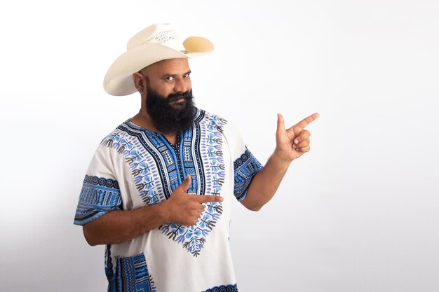 Felice indiano sano uomo di mezza età con berretto da cowboy e camicia hawaiana che punta le mani in alto