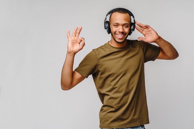 Felice l'uomo africano sorridente ascoltando la musica in cuffia sul muro grigio