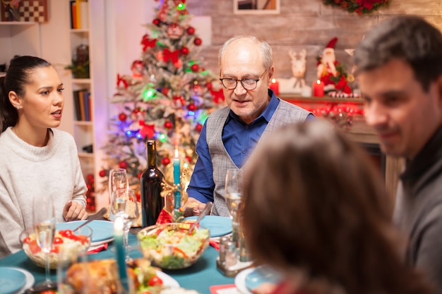 Felice l'uomo anziano a capotavola alla cena di famiglia di natale con cibo delizioso.