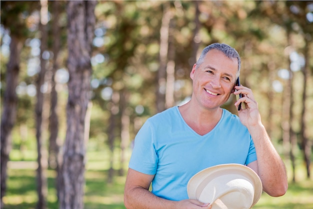 Felice l&#39;uomo parlando telefono su una luminosa giornata di sole e guardando in alto. Uomo maturo sorridente utilizzando il telefono cellulare all&#39;aperto. Ritratto di un uomo in una conversazione attraverso il telefono cellulare.