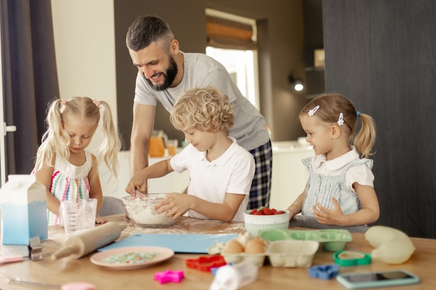 Felice l'uomo positivo che cucina con i suoi figli