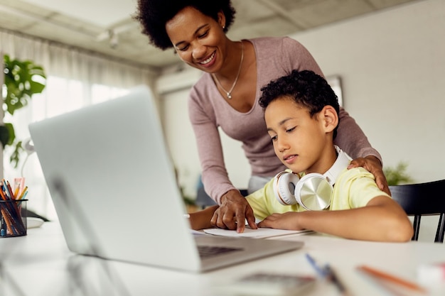 Felice madre afroamericana che assiste suo figlio nei compiti