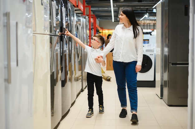 Felice madre con figlio che sceglie il frigorifero nel negozio di elettrodomestici