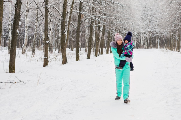 Felice madre e bambina sulla passeggiata nella foresta innevata d'inverno.