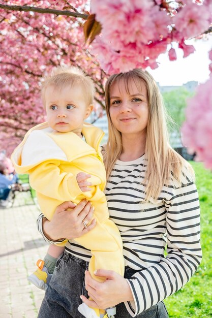 Felice madre e bambino che amano la primavera vicino all'albero di sakura