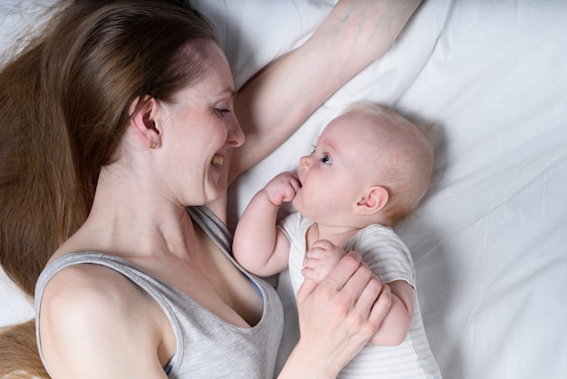 Felice madre e bambino sdraiato sul letto e sorridente. Maternità e genitorialità.