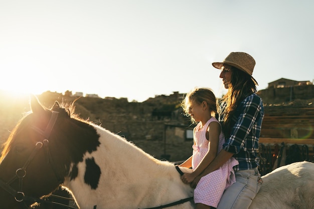 Felice madre e figlia a cavallo al tramonto - Focus sul volto di donna