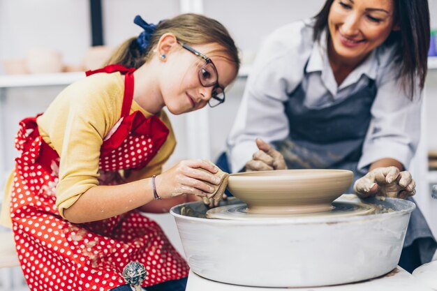 Felice madre e figlia che fanno ceramiche di argilla su una ruota di rotazione.