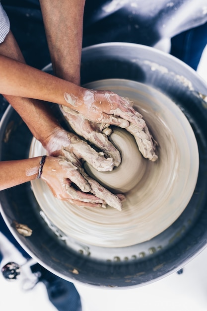 Felice madre e figlia che fanno ceramiche di argilla su una ruota di rotazione.