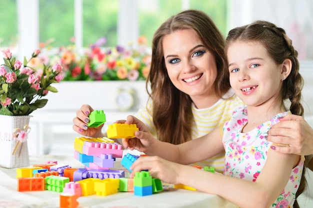 Felice madre e figlia che raccolgono blocchi di plastica colorati