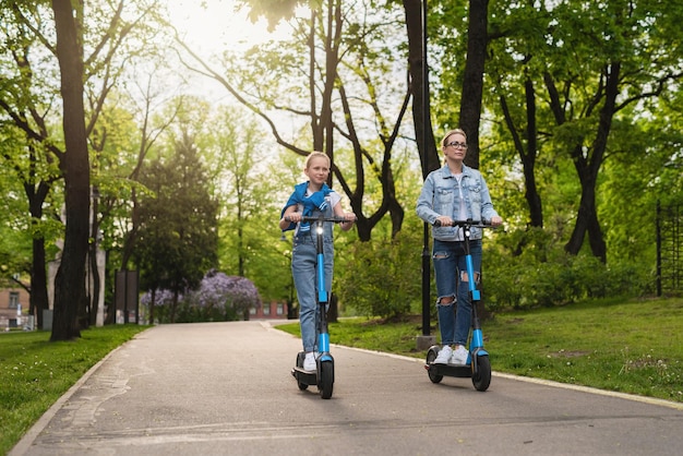 Felice madre e figlia in sella a scooter elettrici nel parco cittadino