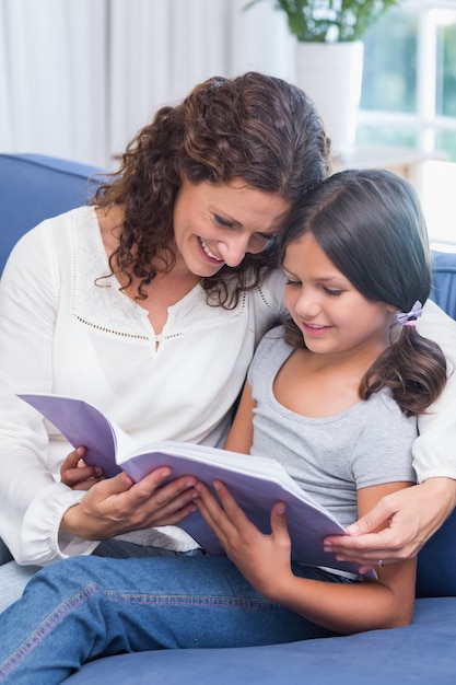 Felice madre e figlia seduta sul divano e leggere il libro