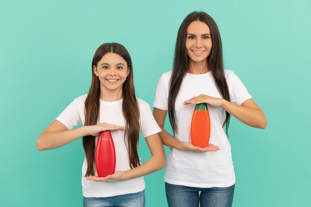 Felice madre e figlia tengono la bottiglia di shampoo su sfondo blu pubblicità