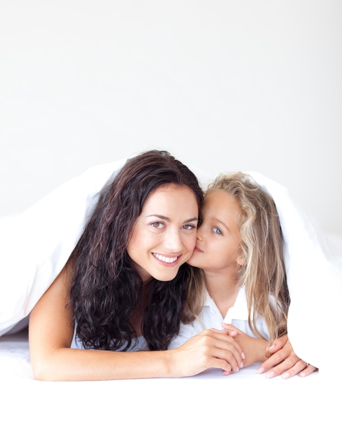 Felice madre e sua figlia guardando la telecamera sul letto