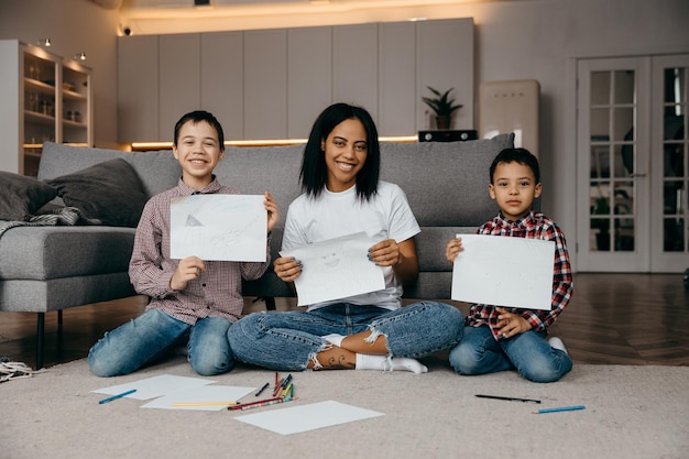 Felice mamma afroamericana che insegna ai suoi figli a disegnare con le matite