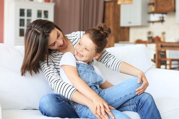 Felice mamma amorevole che abbraccia la piccola figlia, trascorri del tempo insieme a casa.