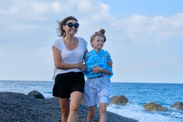 Felice mamma e figlia che si abbracciano camminando insieme lungo la spiaggia. Famiglia, vacanze, felicità, infanzia, comunicazione madre e figlio