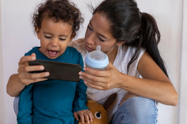 Felice mamma latinoamericana 30 e figlio 2 stanno condividendo un momento mentre utilizzano un telefono cellulare Concetto e tecnologia per la festa della mamma