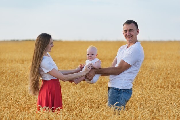 Felice mamma papà e bambino nel campo di grano maturo. Fine settimana con la famiglia all'aperto