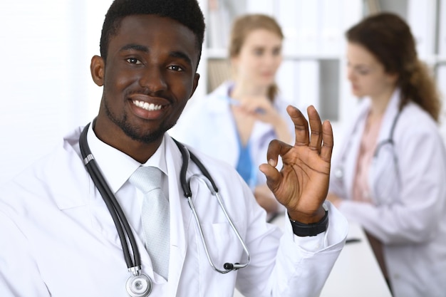 Felice medico maschio afroamericano che mostra segno giusto