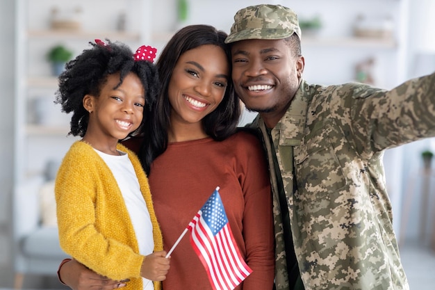 Felice militare nero prendendo selfie con moglie e figlia