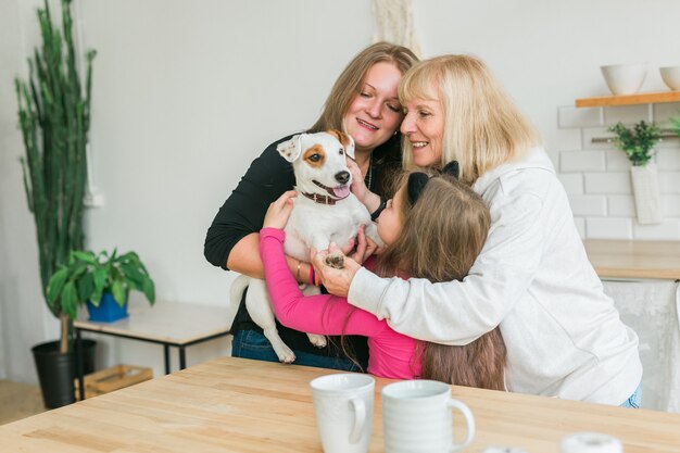 Felice nipote e nonna e figlia che si divertono con il cane jack russell terrier. La nonna abbraccia il nipote a casa. Relazione, famiglia e concetto di tre generazioni.