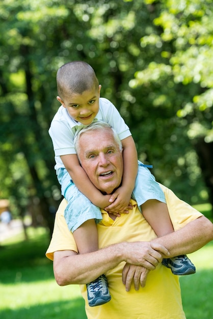 felice nonno e bambino si divertono e giocano nel parco in una bella giornata di sole