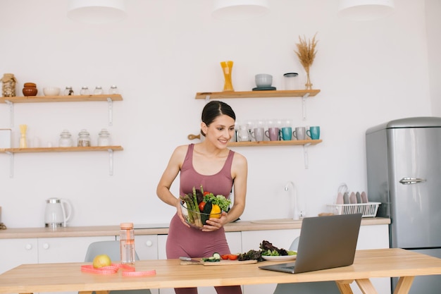 Felice nutrizionista blogger donna atletica prepara un'insalata con verdure fresche