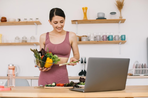 Felice nutrizionista blogger donna atletica prepara un'insalata con verdure fresche