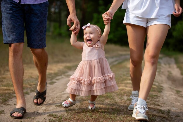 Felice oney orecchio vecchia ragazza è tenuta da papà e mamma Bambino che cammina con i genitori