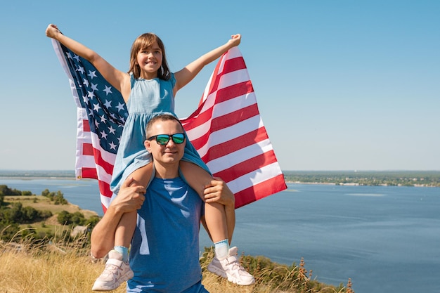 Felice padre di famiglia e bambino con bandiera usa godersi la natura in una giornata di sole