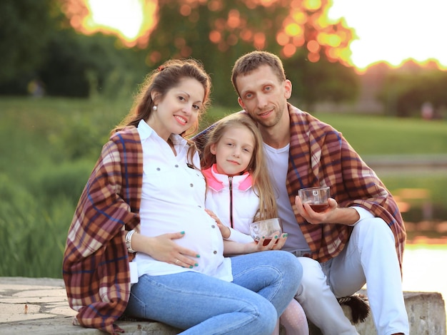 Felice padre di una figlia e una mamma incinta al picnic