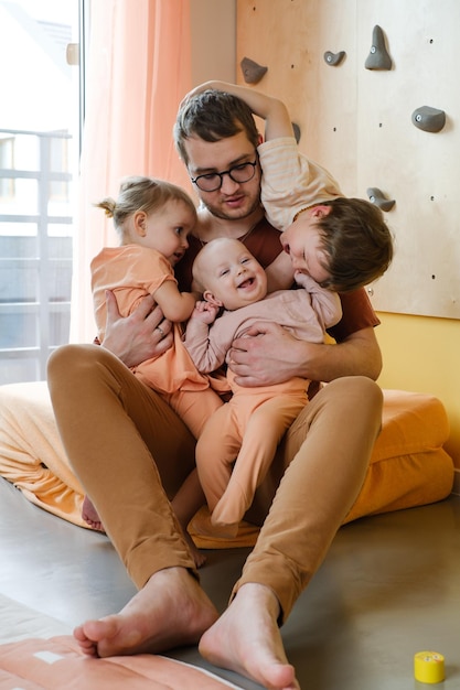 Felice padre di una grande famiglia con bambini piccoli dell'albero che giocano a casa