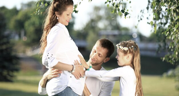 Felice padre e bambina che abbracciano la madre incinta su un wa