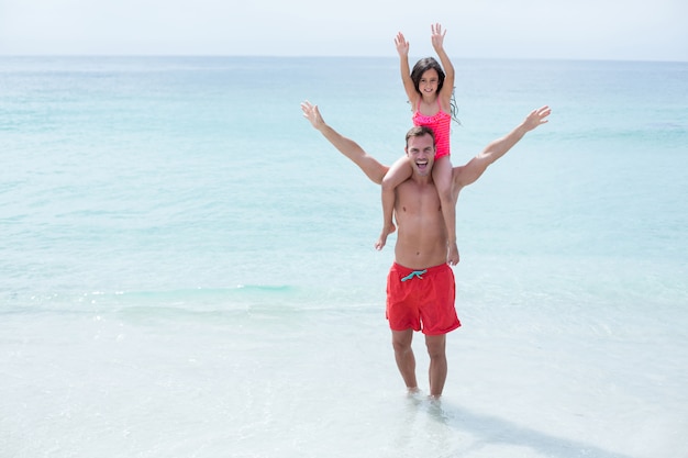 Felice padre e figlia con le braccia alzate in spiaggia