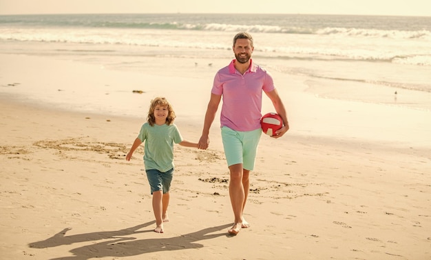 Felice padre e figlio camminano sulla spiaggia estiva con la famiglia della palla