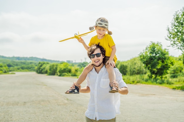 Felice padre e figlio che giocano con l'aeroplano giocattolo sullo sfondo della vecchia pista Viaggiando con il concetto di bambini