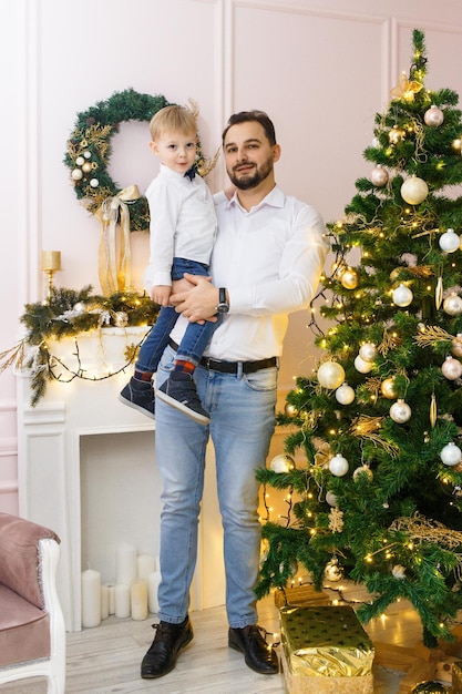 Felice padre e figlio contro l'albero di Natale con palle di Natale e ghirlanda leggera