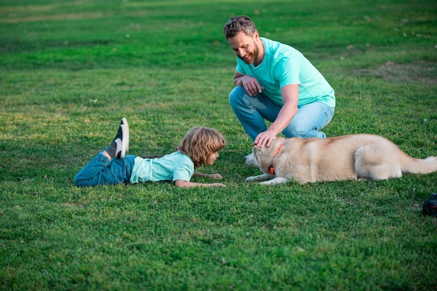 Felice padre e suo figlio che giocano con il cane nel parco estivo