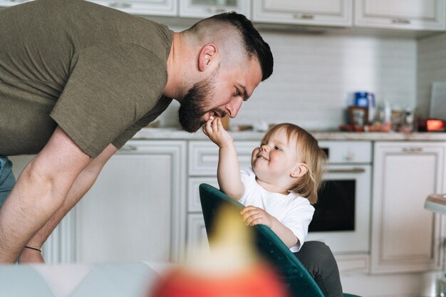 Felice padre giovane che si nutre e si diverte con la piccola figlia della bambina in cucina a casa