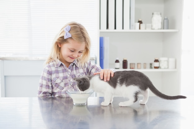 Felice padrona che accarezza il suo gatto mentre beve latte